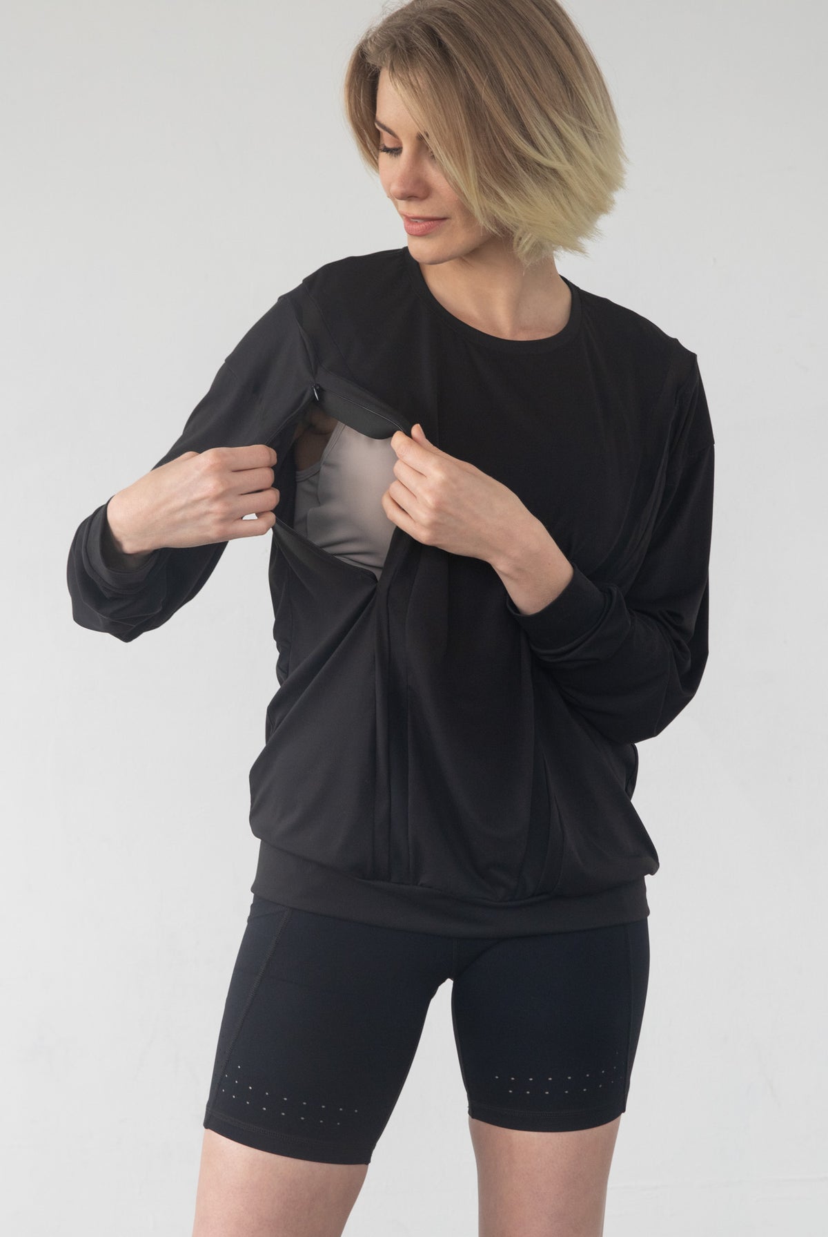 '- Model lifting Ivy nursing top to show hidden nursing access panel
- Discreet nursing access on Ivy top – breastfeeding in style