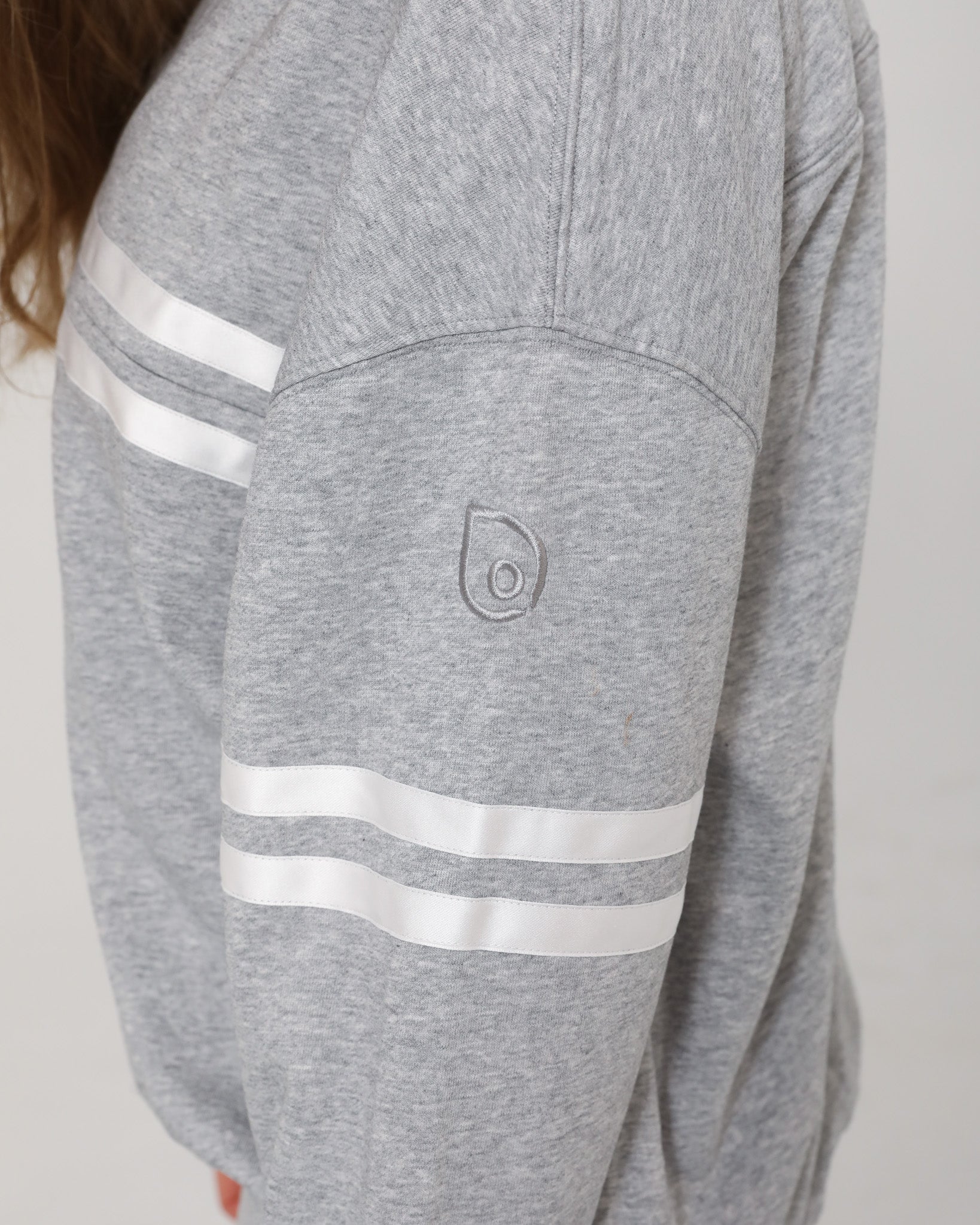 Detailed close-up of the embroidered Sweat & Milk logo on the sleeve of the Celine Nursing Pullover in heather gray.