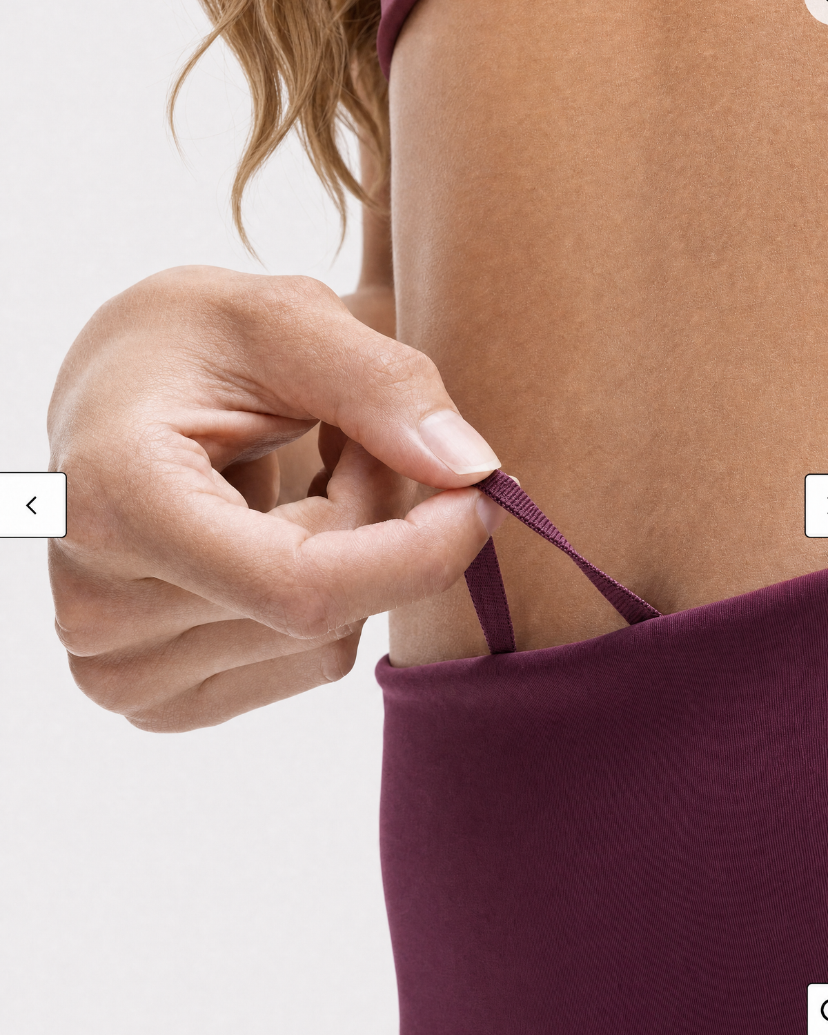 A model wearing high-waisted, full-length postpartum leggings from sweat and milk in a deep plum purple color or bordeaux color shown from the waist down against a light gray studio background, close up shot for the draw string