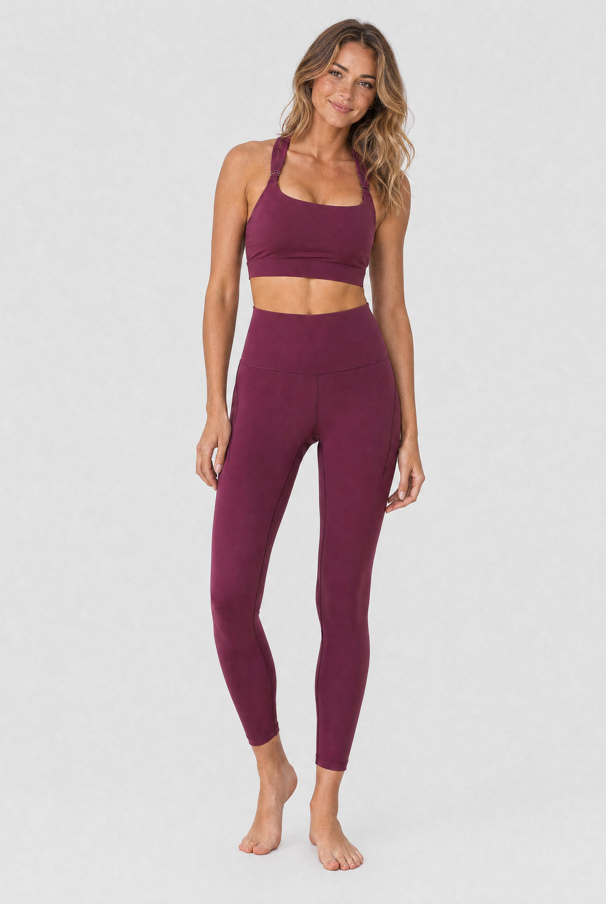 A model wearing high-waisted, full-length postpartum leggings from sweat and milk in a deep plum purple color or bordeaux color shown from the waist down against a light gray studio background, full body shot