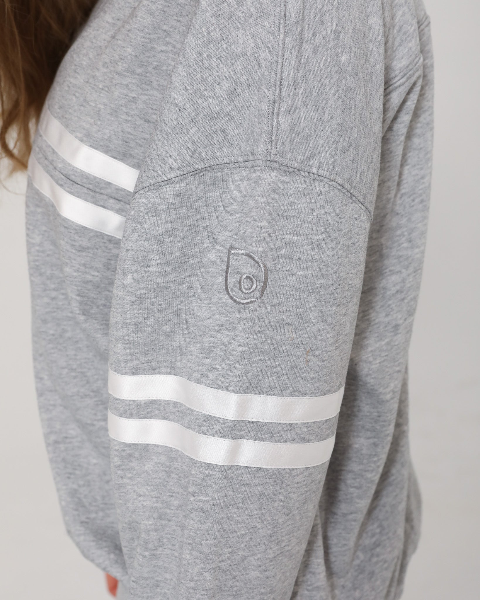 Detailed close-up of the embroidered Sweat & Milk logo on the sleeve of the Celine Nursing Pullover in heather gray.
