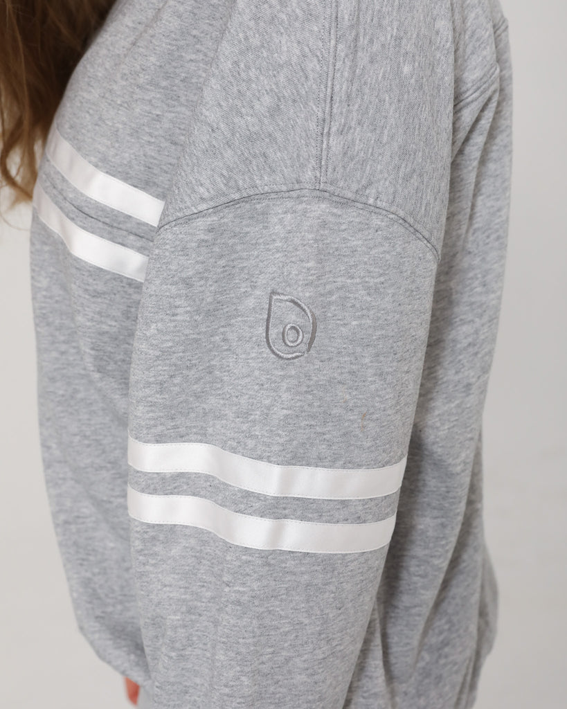 Detailed close-up of the embroidered Sweat & Milk logo on the sleeve of the Celine Nursing Pullover in heather gray.
