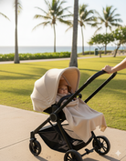 a cashmere poncho is folded into a baby blanket to cover a baby's legs in a stroller
