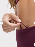 A model wearing high-waisted, full-length postpartum leggings from sweat and milk in a deep plum purple color or bordeaux color shown from the waist down against a light gray studio background, close up shot for the draw string
