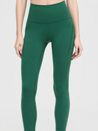 A model wearing high-waisted, full-length pine green leggings against a light gray studio background, front shot