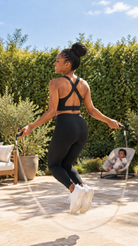 Mom jumping rope in the Venice 3 nursing sports bra in Noir, baby watching from a bouncer